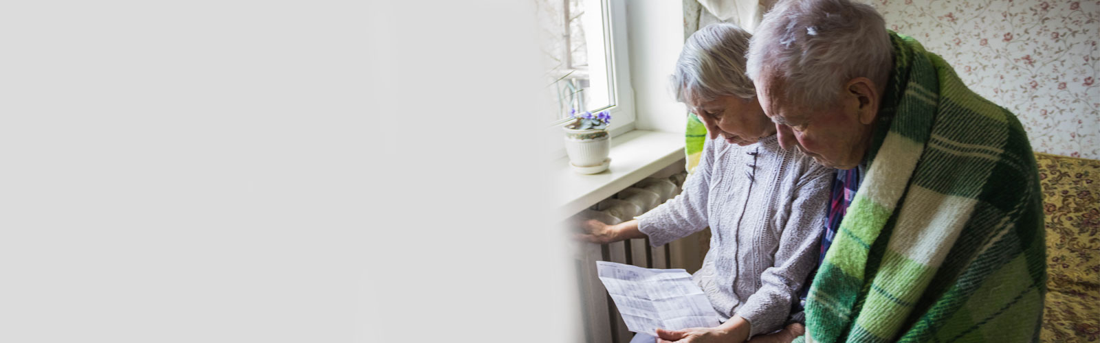 An older couple look anxiously at their heating bill