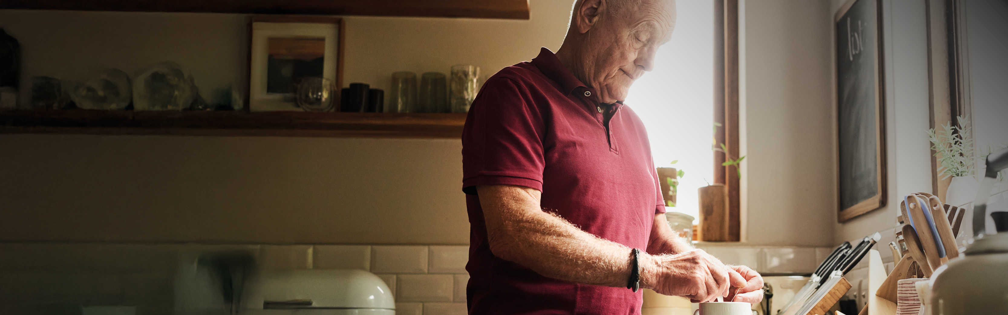 An older man in a red shirt, looking downwards