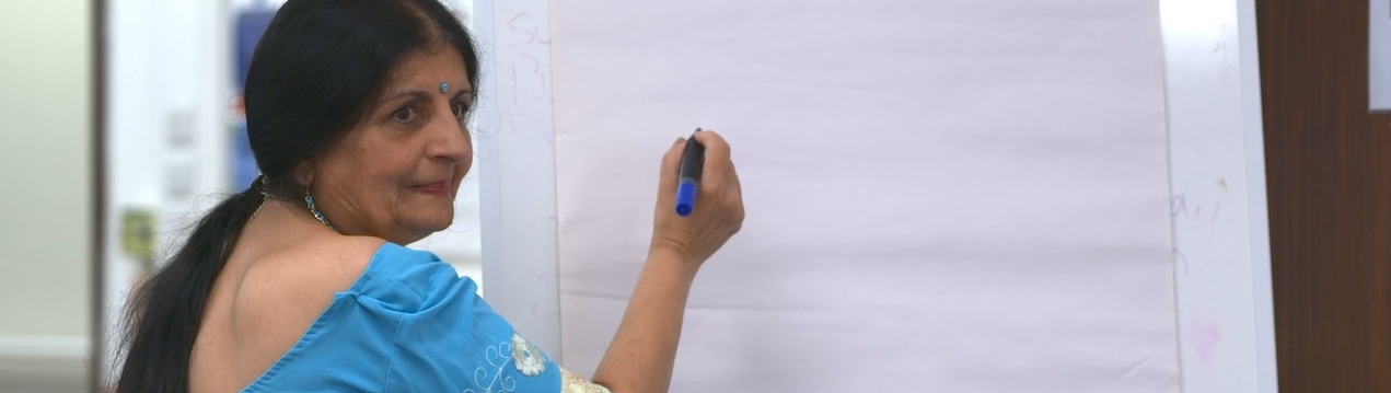 A lady in a sari writes on a whiteboard