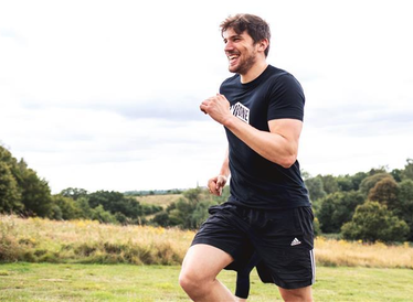 A man with a beard, running outdoors