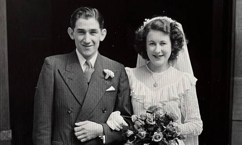A black-and-white photo of a young man and woman on their wedding day