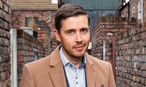 Actor Gareth Pierce, playing Todd Grimshaw on Coronation Street, stands in one of the street's red brick gulleys