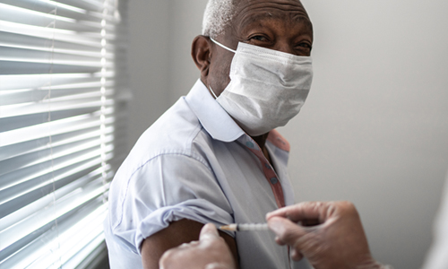 An older man wearing a facemask receiving the vaccine