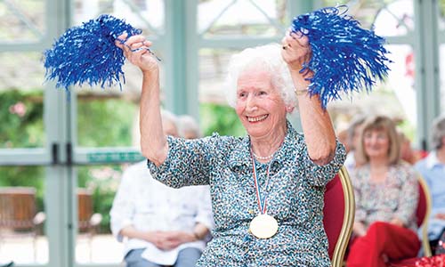 An older lady using pompoms at an exercise class