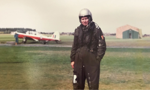 Old photo of an RAF pilot in full kit and standing in front of a plane.