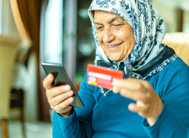 Woman on smartphone holding bank card whilst transferring money